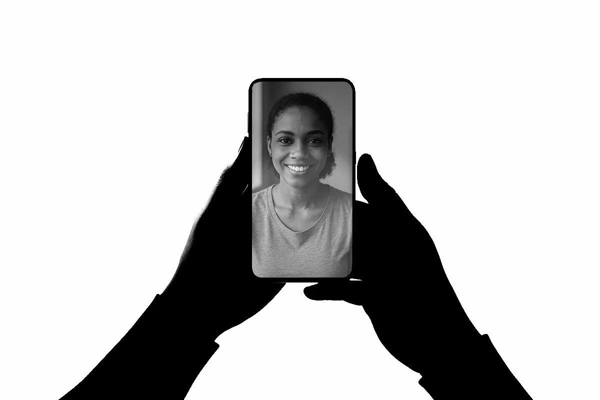 Two hands holding a phone on a video call with a smiling assistant